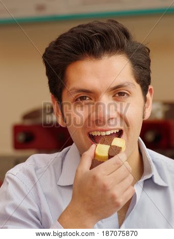 Close up of a young businessman eating cookie.