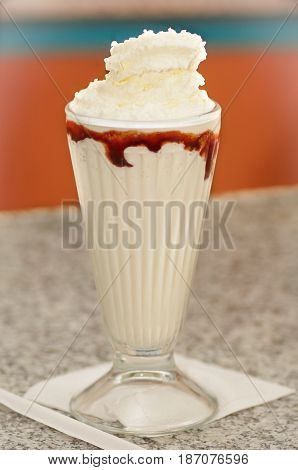 Delicious vanilla milkshake with syrup and cream on top.
