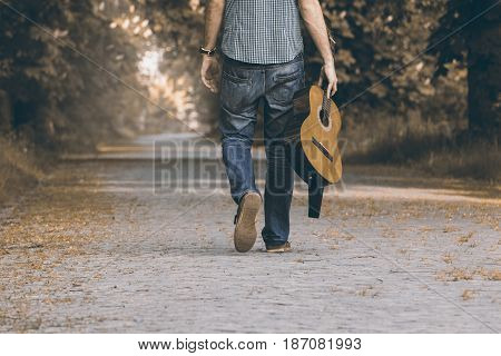Free travel with guitar. With music instrument on the trip. Person is walking with guitar on the path.