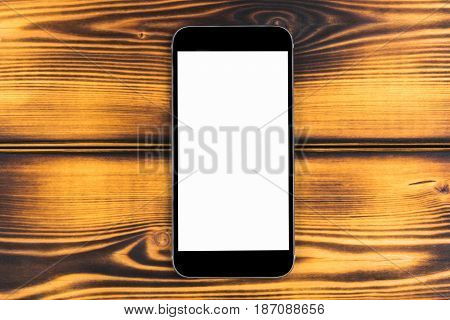Mobile phone with blank screen mock up isolated on burned wood table background. Smartphone on wood table. Smartfone white