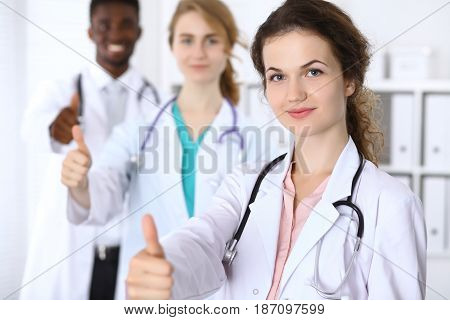 Happy doctor woman with medical staff at the hospital. Thumbs up.