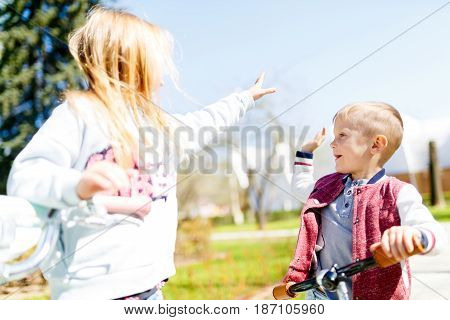 Girl with boy makes winning blow to hands of park in afternoon
