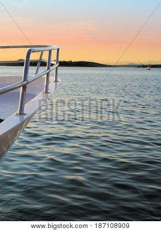 Prow of boat against sun setting at sea