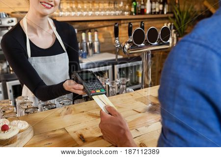 Man making payment on credit card reader machine at cafe shop
