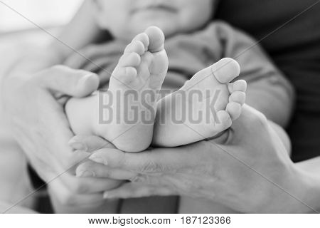 Close Up View Of Child's Feet In Mother's Hands. Photo Made In Black And White