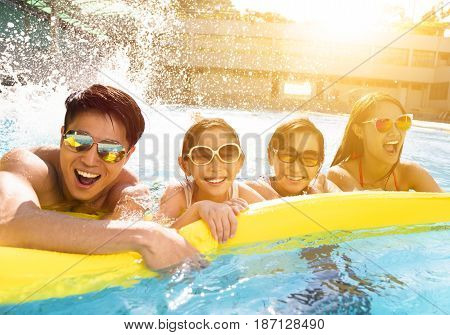 Happy asian  family playing in swimming pool