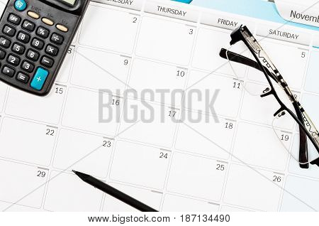 calendar schedule on work table and calculator pencil eye glasses.