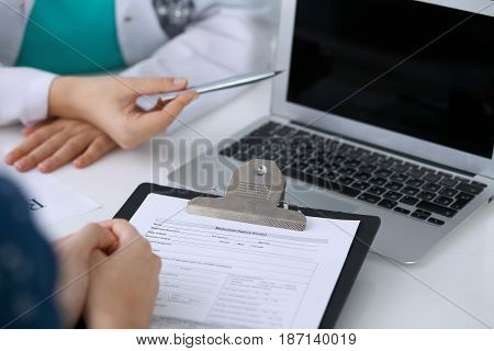 Close up of a doctor and  patient  sitting at the desk while physician pointing into laptop computer. Medicine and health care concept.