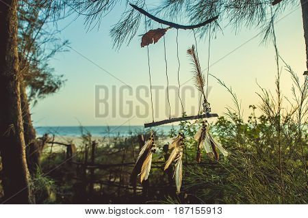 Amulet Of Sticks And Feathers Against The Background Of The Ocean During Sunset