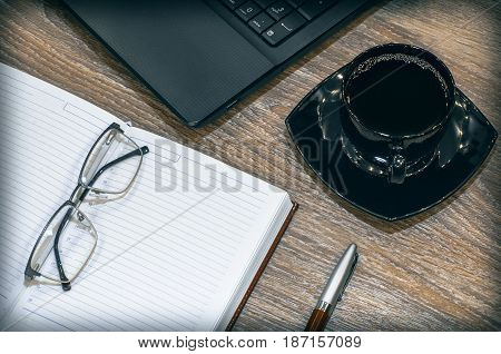 Education or business flat layout concept. Black Laptop keyboard phone tea cup planner pen on wooden table background.