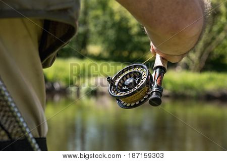 Rod with reel hunting trout. In the background the trout river Otava South Bohemia. Czech Republic.