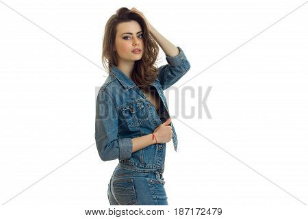sexy young girl in jeans suit stands sideways and posing for the camera isolated on white background