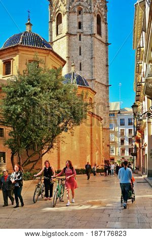 VALENCIA, SPAIN - APRIL 23, 2016: Residents and tourists walk along street near tower Miguelete (Micalet) is known as bell tower of the Cathedral of Valencia. This is a Gothic tower 51 meters high
