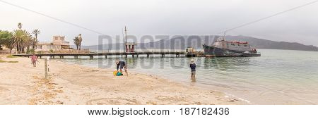LANGEBAAN SOUTH AFRICA - MARCH 31 2017: A boat anchored at a pier and anglers at Langebaan on the Atlantic Coast of the Western Cape Province