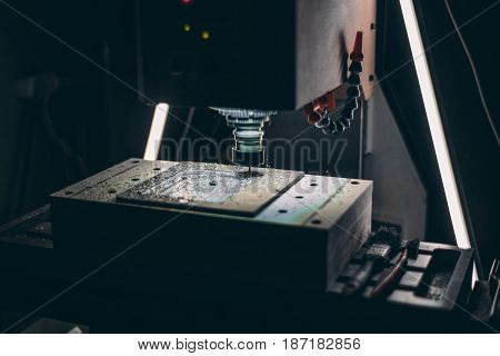 Working CNC milling machine cutting piece of aluminum with high rotation speed in dark settings: static rotating tool and moving table a lot of metal shavings from drilling LED backlight from lamps
