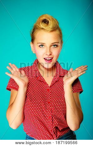 Shocking amazed astonished gestures concept. Shocked lovely pin up young girl holding head with hands. Studio shot on blue background