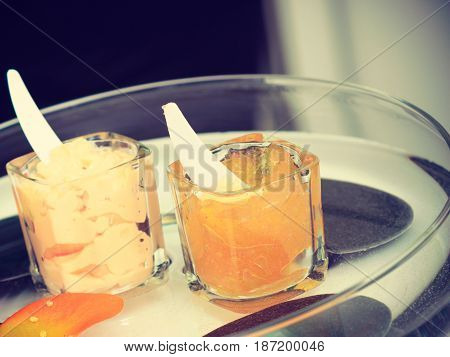 Manicure and pedicure salon equipment concept. Two cups with colorful cosmetic paraffin on glass plate.