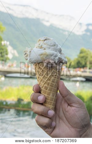A Man Holding an Ice Cream Cone with a Scoop of Stracciatella and a Scoop of Chocolate in Summer in Annecy, France