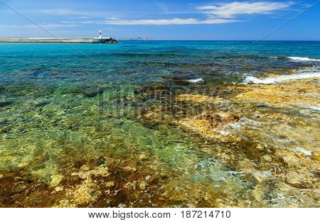 Waves break on rocky shore. Coast and beach resort village. Clear day at sea. Crete island, Greece, Beach Caves