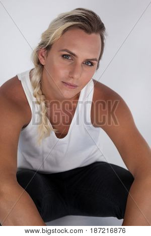 Portrait of transgender woman sitting over gray background