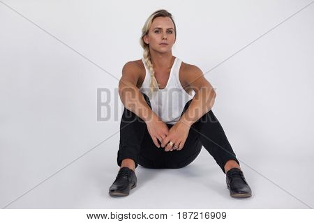 Portrait of transgender woman sitting over gray background