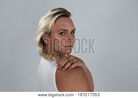 Portrait of transgender woman looking over shoulder against gray background