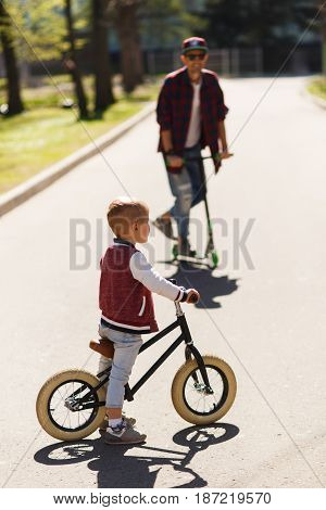 Dad with son on scooters in park during day