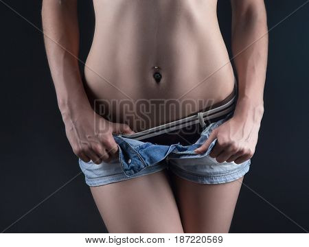Woman in jeans shorts with slim shape on dark background