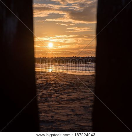 Sunset through piles at the North Sea beach of Cadzand Holland