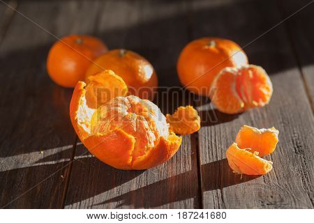 Ripe sweet tangerines with juicy peeled  on wooden roustic background with sunlight