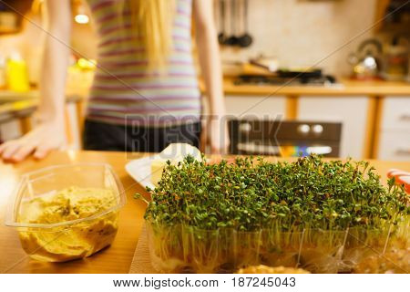 Cuckooflower on wooden kitchen table. Woman making delicious vegetarian sandwich.