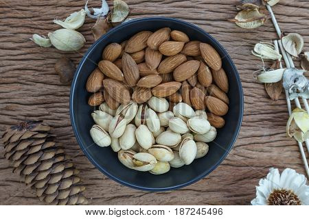 appetizer roasted healthy delicious salt pistachios cashew nuts and almonds food in black bowl on wooden table background.