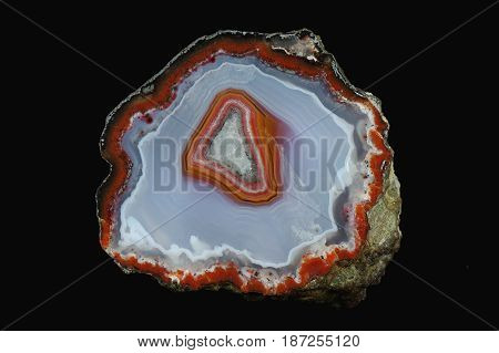 A cross section of the agate stone. Colorful center against the background of gray-blue and white chalcedony. Origin: Asni Atlas Mountains Morocco.