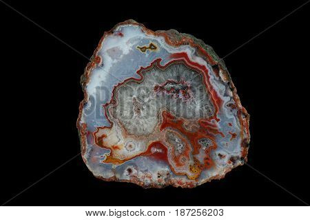 A cross section of the agate stone. The center is filled with quartz. Multicolored silica rings colored with metal oxides are visible. Origin: Asni Atlas Mountains Morocco.