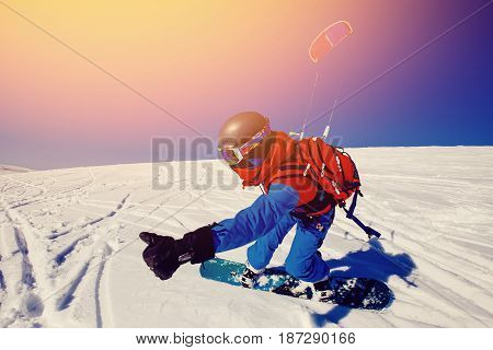 Snowboarder with a kite on fresh snow in the winter in the tundra of Russia against a clear blue sky. Teriberka Kola Peninsula Russia. Concept of winter sports snowkite.