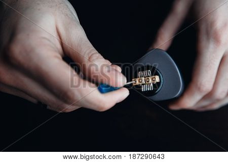 male master installs a coyle. Spiral for electronic evaporator and cigarette. Vape, vaping. Firing a coil.