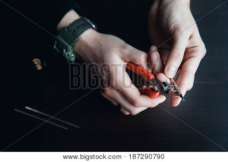 male master installs a coyle. Spiral for electronic evaporator and cigarette. Vape, vaping. Pliers, wire, fichral, coil, screwdriver
