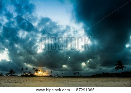 Sunset on the beach with storm clouds while the sun is hiding among the dunes