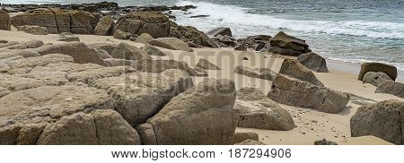 Australian panoramic rocky seafront beach view with rocks boulders sand beach surf waves and ocean