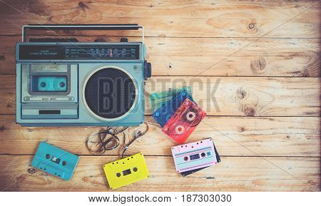 Top view hero header - retro technology of radio cassette recorder music with retro tape cassette on wood table. Vintage color effect styles.