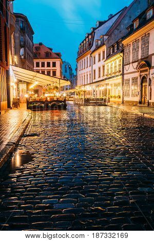 Riga, Latvia - July 3, 2016: Cafe In Lighting At Evening Or Night Illumination In Old Town In Skarnu Street