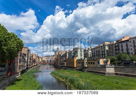 Girona, Catalonia old town green embankment with buildings and clouds on the blue sky