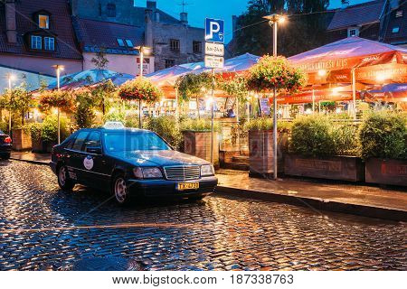 Riga, Latvia - July 3, 2016: Taxi Car Mercedes-Benz W140 Wait Clients Near Open Air Leisure Venue Recreation Center Egle In Evening Or Night Illumination In Old Town On Kalku Street