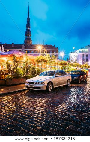 Riga, Latvia - July 3, 2016: Sedan Car BMW 5 Series E39 Parking Near Open Air Leisure Venue Recreation Center Egle In Evening Or Night Illumination In Old Town On Kalku Street