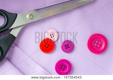 needlework and tailoring concept - scissors, sewing buttons and cloth