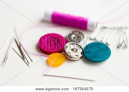 needlework and tailoring concept - sewing buttons, needles, pins and thread spool