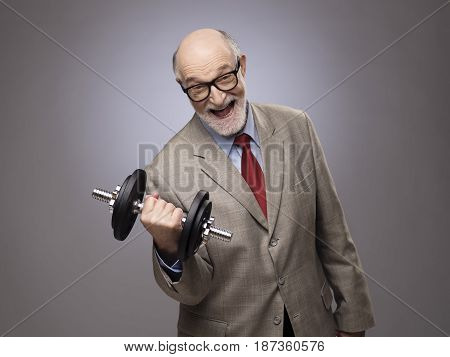 Happy funny senior man in suit with dumbbell power concept