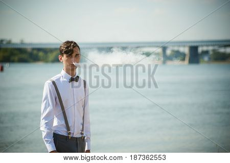 Young Skinny Man, Elegantly Stylishly Dressed In White Shirt, Trousers With Suspenders And Bow Tie.