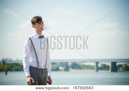 Young Skinny Man, Elegantly Stylishly Dressed In White Shirt, Trousers With Suspenders And Bow Tie.