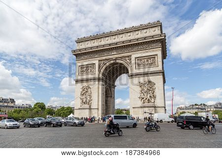 Paris, France - May 13, 2017: The Arc de Triomphe against a blue sky with traffic in front of it
